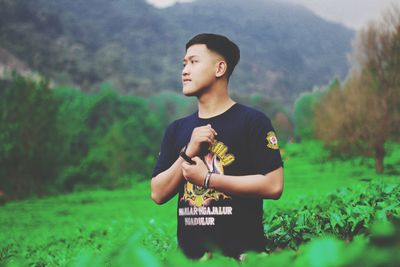 Young man looking away while standing on field