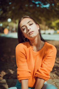 Young woman looking away while standing against tree