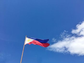 Low angle view of flag flags against blue sky