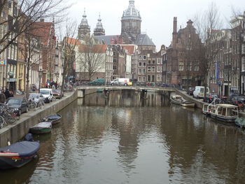 Sailboats moored on canal amidst buildings in city