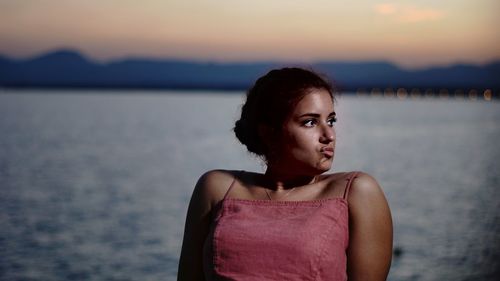 Portrait of woman standing against sea during sunset