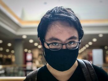 Close-up portrait of a serious young man against skylight and ceiling in shopping mall.