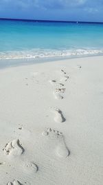 Footprints on sand at beach against sky