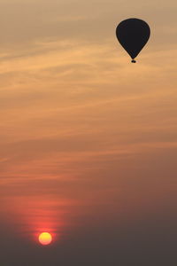 Silhouette hot air balloon against orange sky