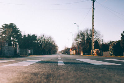 Street by trees against clear sky