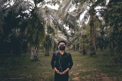 Portrait of young man wearing mask standing in forest