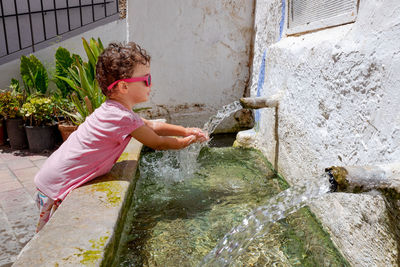 Cute girl cleaning hands by drink fountain