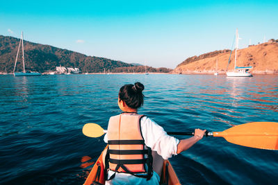 Rear view of woman kayaking in sea