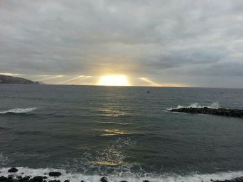 Scenic view of seascape against cloudy sky during sunset