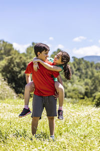 Full length of brother standing with girl on field