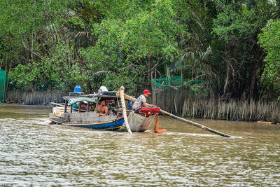 People on boat in river against trees in forest