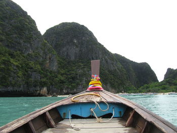 Longtail boat in sea against rocky mountains at krabi province