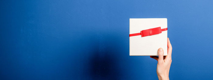 Close-up of hand holding paper flag against blue wall