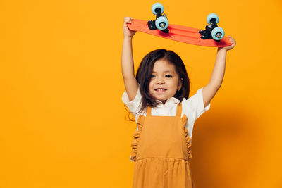 Portrait of smiling young woman holding toy against yellow background