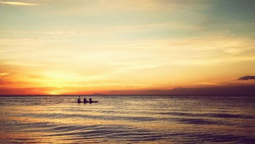 Silhouette people on beach against sky during sunset