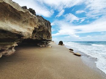 Rock formation on beach against sky
