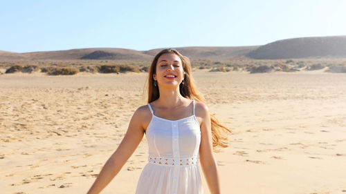 Smiling young woman with eyes closed standing at beach