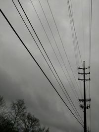 Low angle view of electricity pylon against cloudy sky