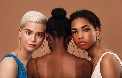 Portrait of beautiful women with touching heads against brown background