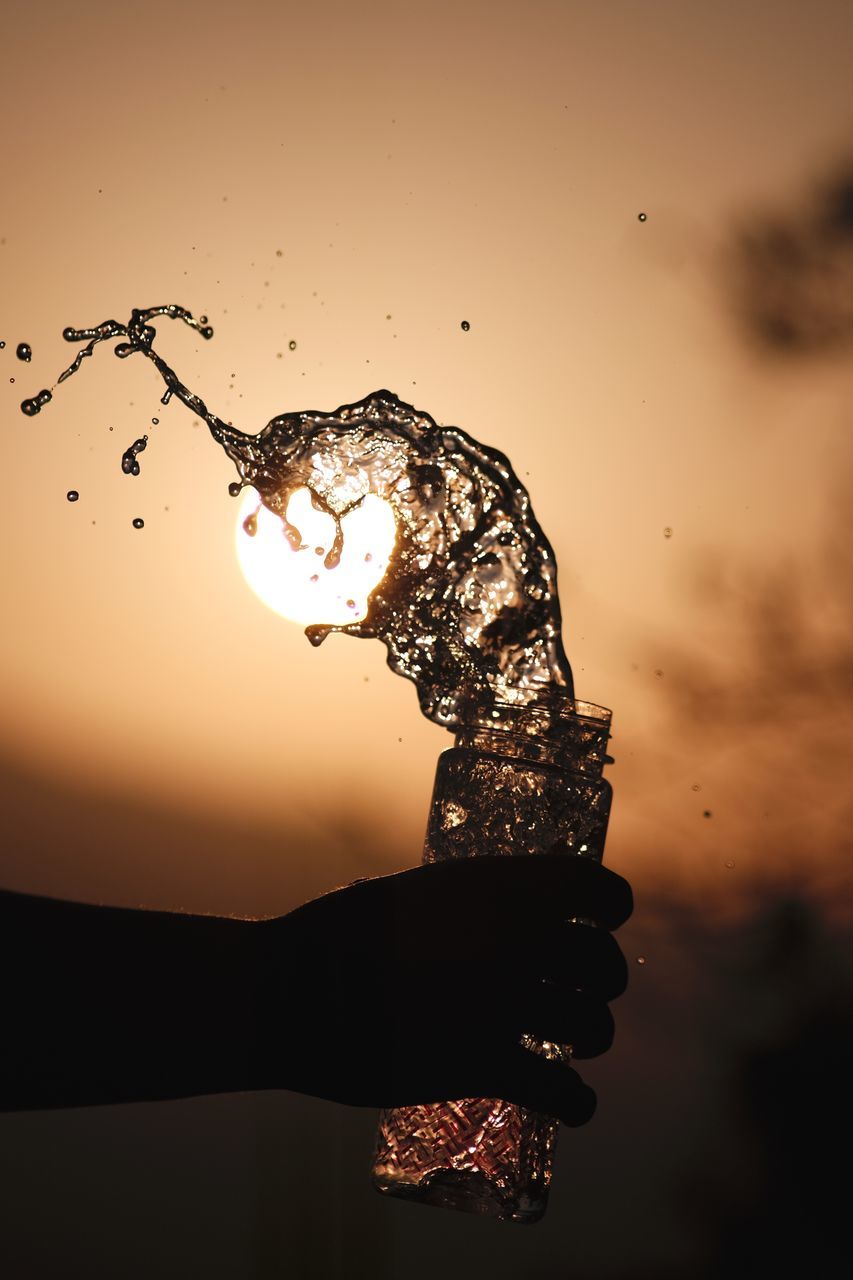 CLOSE-UP OF WATER SPLASHING IN SEA AGAINST SKY DURING SUNSET