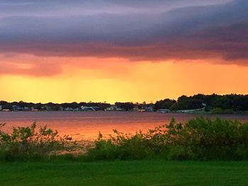 Scenic view of lake against cloudy sky at sunset