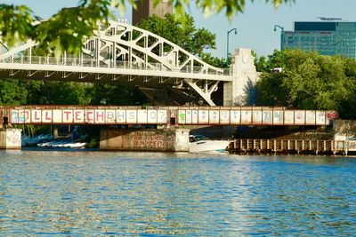 Bridge over river in city against sky
