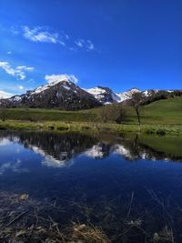 Scenic view of lake and mountains against blue sky