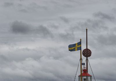 Low angle view of crane against cloudy sky