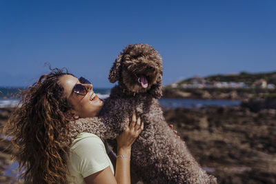Side view of young woman with dog against sky
