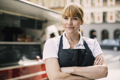 Portrait of confident chef with arms crossed standing in city