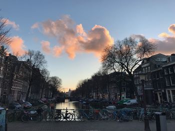 Bicycle by bare trees against sky during sunset