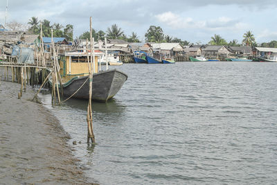 Sailboats moored on sea against buildings