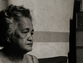 Portrait of woman looking away against wall