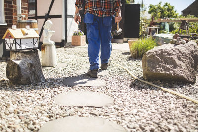 Low section of senior man holding hammer while walking at yard