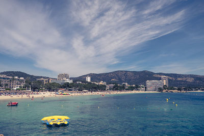 Scenic view of sea by cityscape against sky