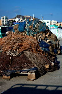 Fishing net on pier at harbor against clear blue sky