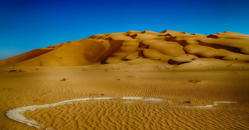 Sand dune in desert against clear blue sky