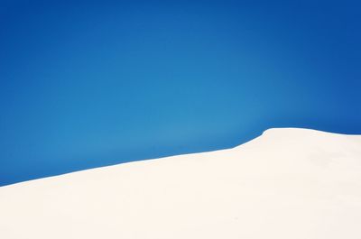 Scenic view of snow covered mountain against clear blue sky