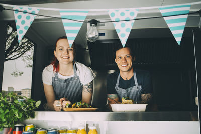 Smiling owner and assistant standing in food truck