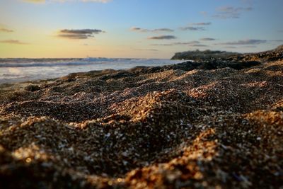 Surface level of sea shore against sky during sunset