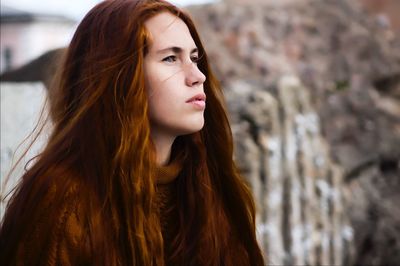 Thoughtful young woman with long brown hair looking away outdoors