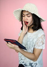 Young woman looking away while standing against wall