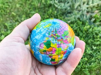 Close-up of person holding globe over grass