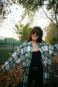 Portrait of smiling young woman standing against trees