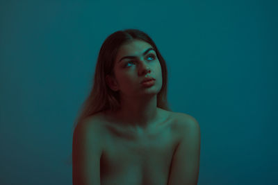 Portrait of young woman against blue background