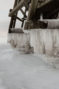 Frozen sea by building against sky