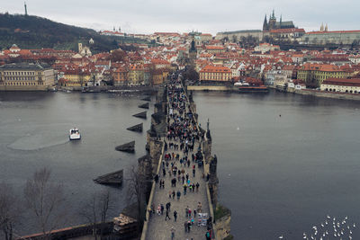 High angle view of people on footbridge over river against sky in city