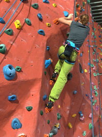 Rear view full length of woman climbing wall