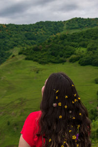 Rear view of woman walking on field against sky