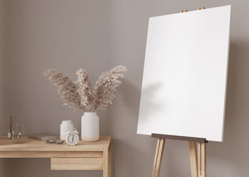 Empty vertical canvas on wooden easel in modern and cozy room. canvas mock up, interior